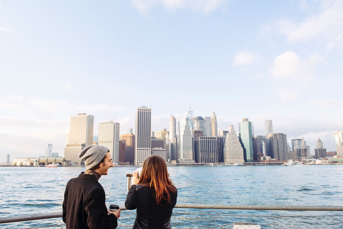 A couple stands on a railing, taking in the vibrant sights of New York City around them.
