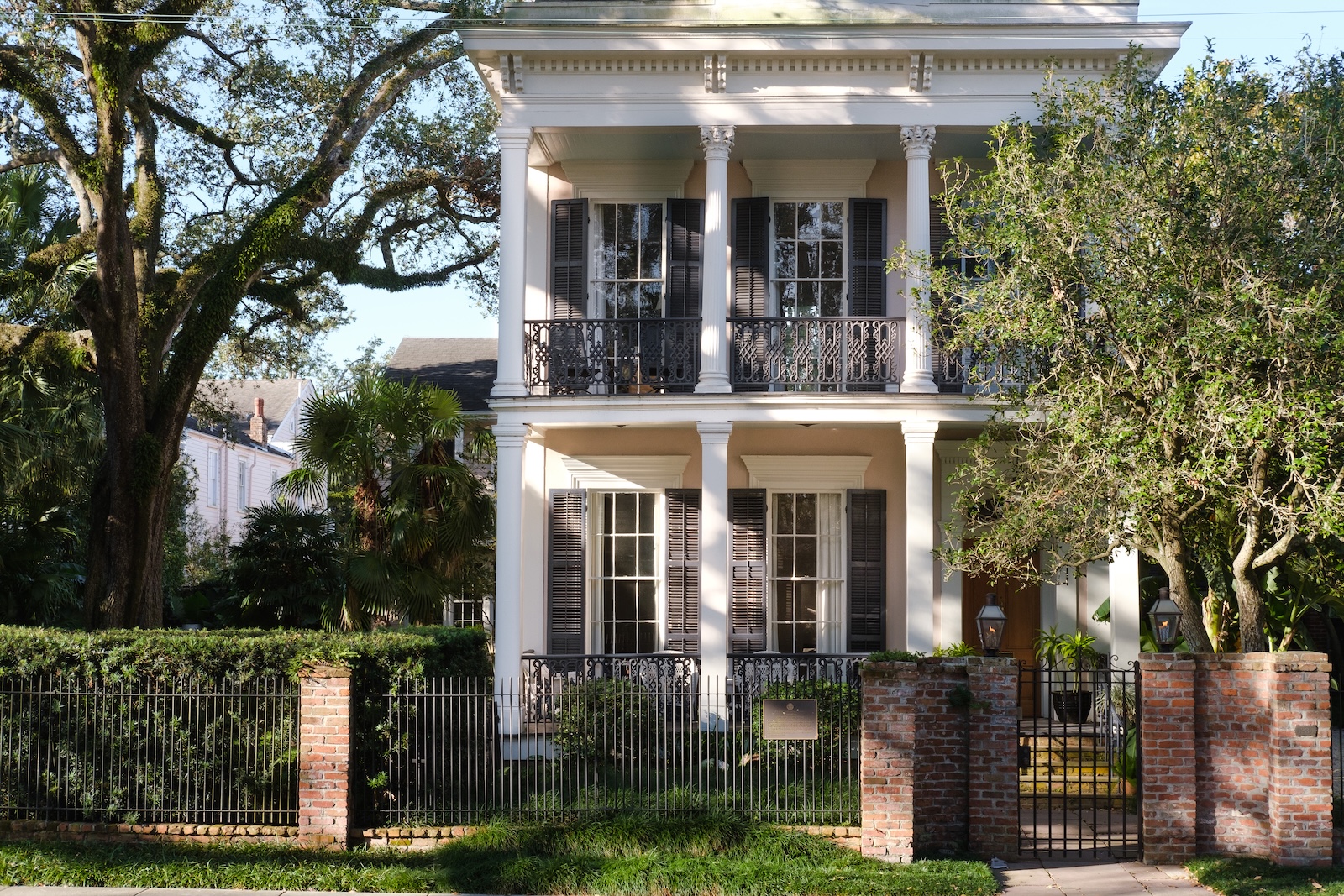 A two-story house with a large porch and fence, located in the Garden District
