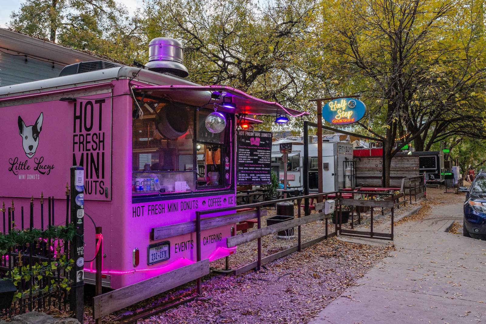 A pink food truck with a "Hot Fresh Mini Donuts" sign parked in the Rainey Street Historic District.