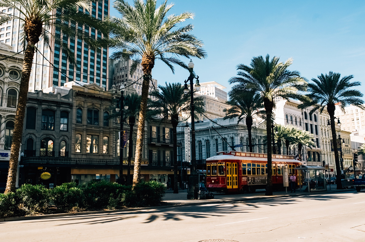 A classic red trolley travels along a bustling street in New Orleans, Louisiana, showcasing the city's iconic transport.