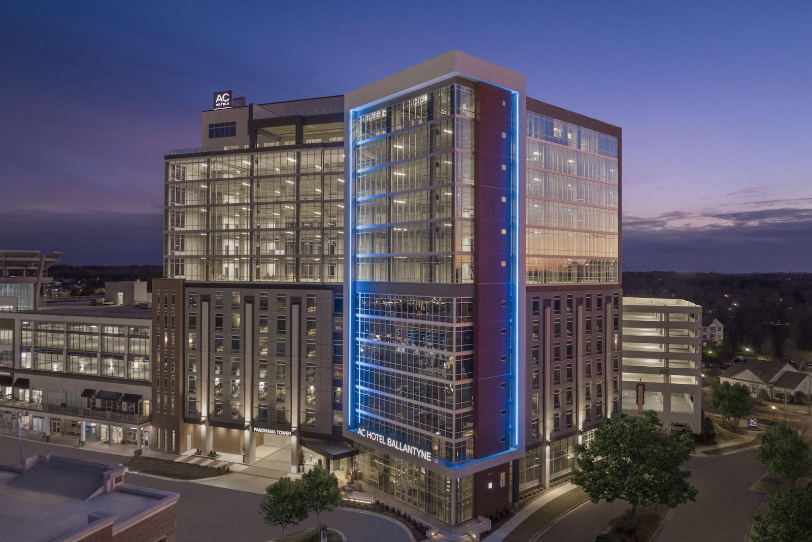 The AC Hotel Ballantyne illuminated at night, showcasing its modern architecture against a dark sky.