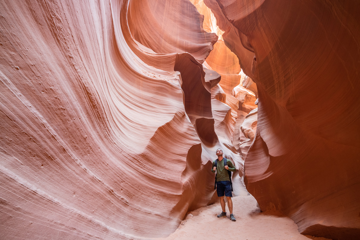 A man stands in the heart of Antelope Canyon, surrounded by stunning rock formations and vibrant colors.