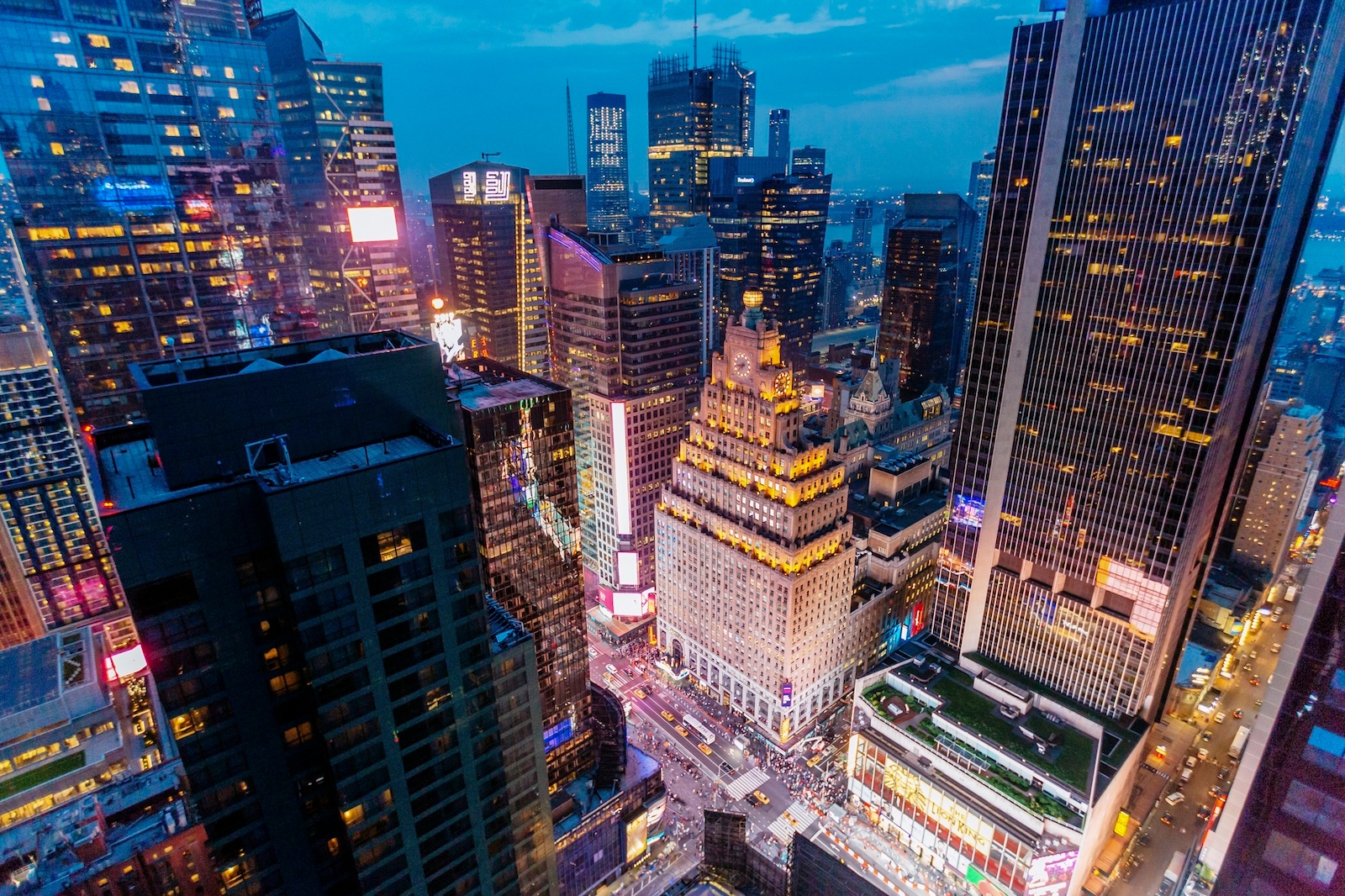Aerial view of New York City at dusk, showcasing the skyline illuminated by city lights against a twilight sky
