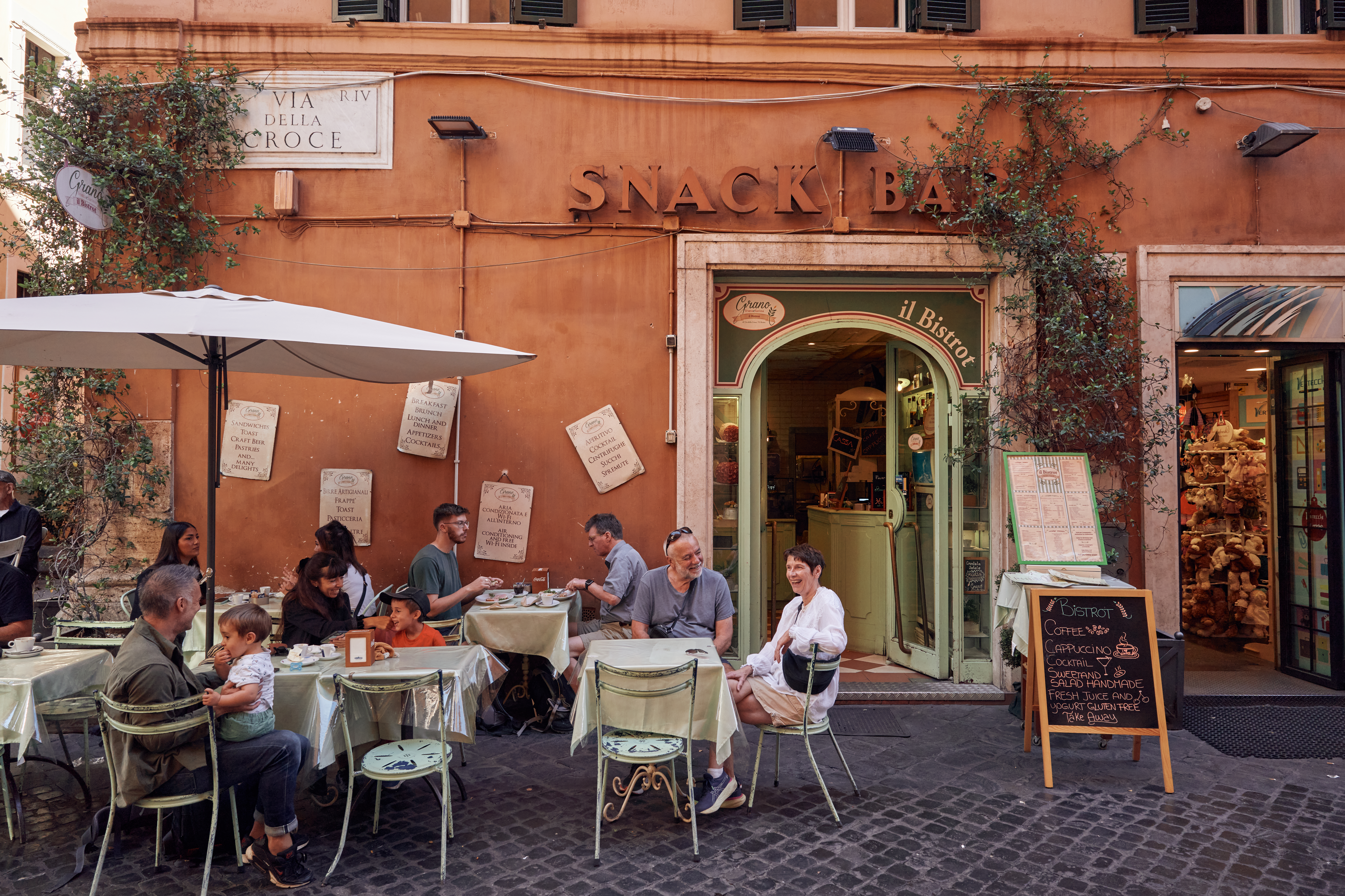 People dining outdoors at a café on a street in Rome.