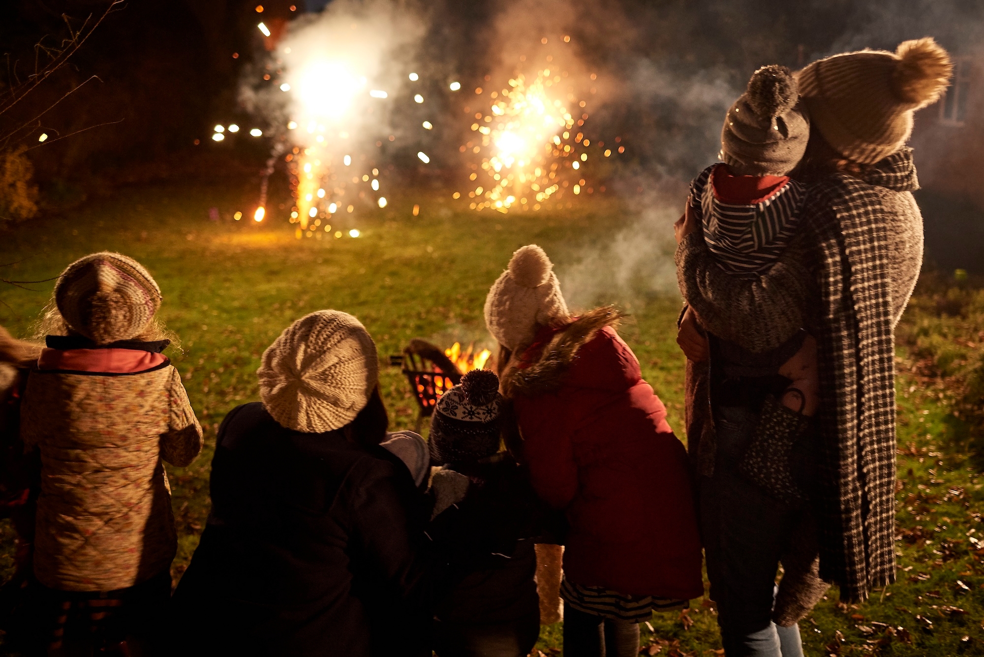 A family enjoys a vibrant display of fireworks against the night sky during Bonfire Night in the UK.