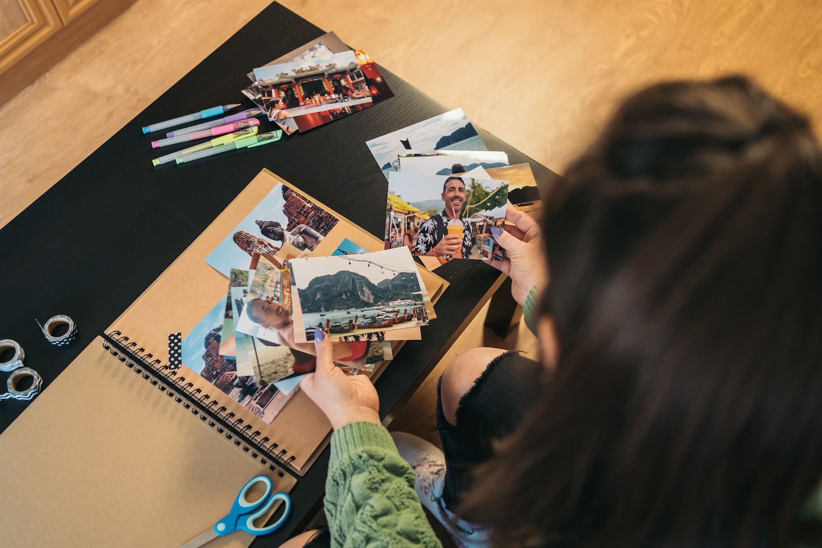 A woman holds a photo album and scissors, preparing to recreate images from her cherished old album.