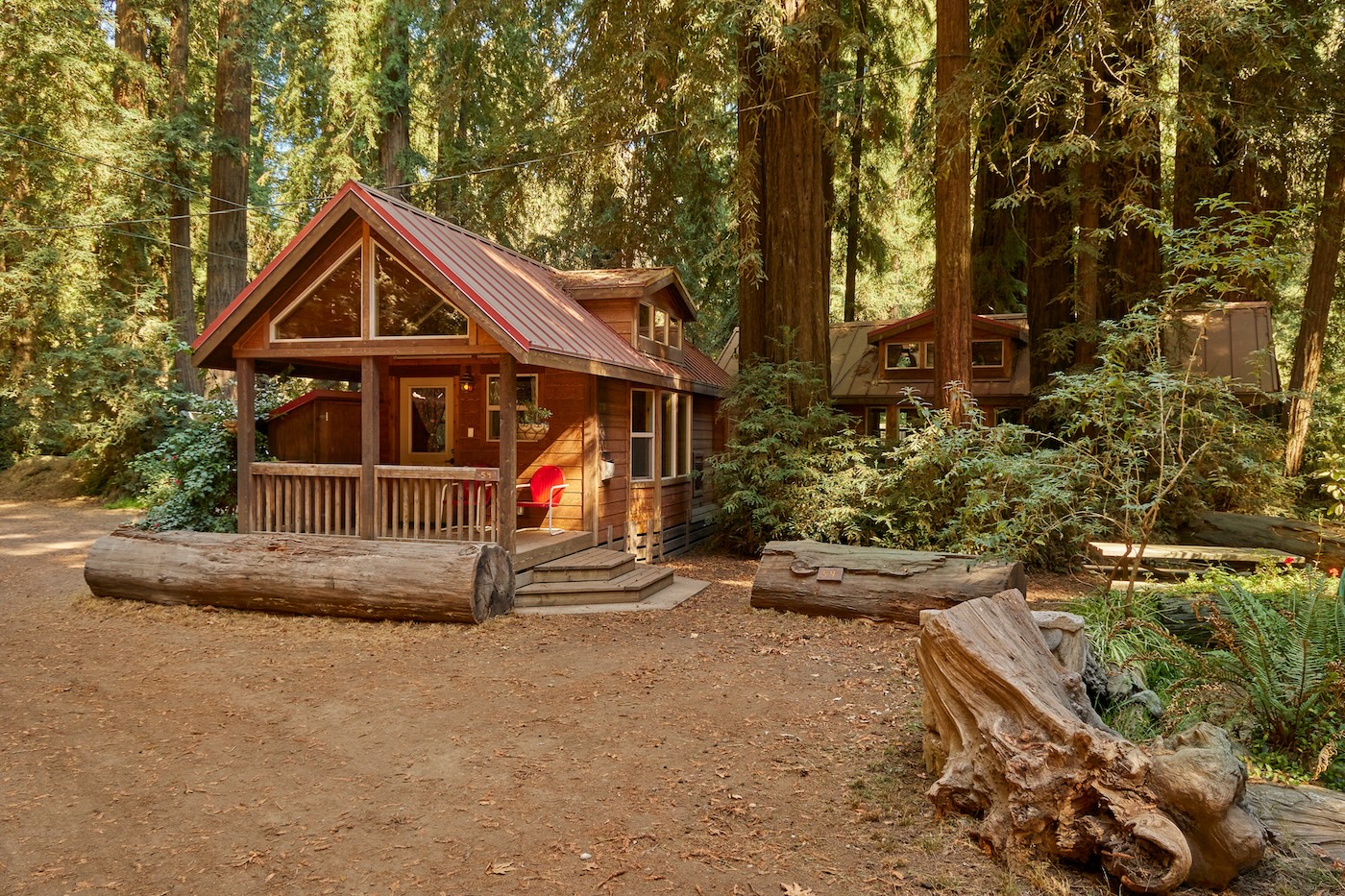 A charming cabin with a red roof surrounded by trees at Big Sur Campground in California, ideal for a peaceful retreat.