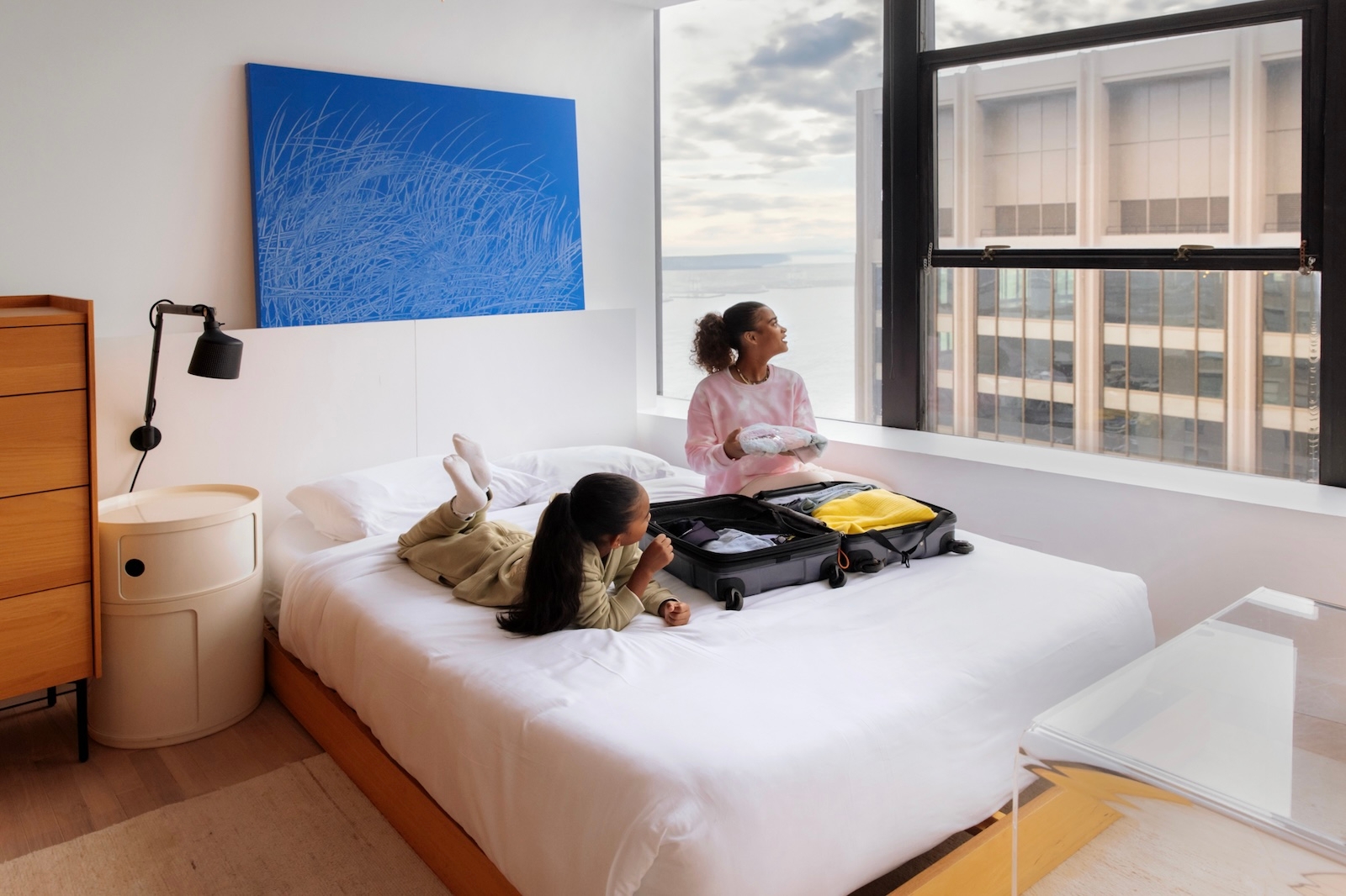 Two women sitting on a bed, engaged in conversation and sharing a ...