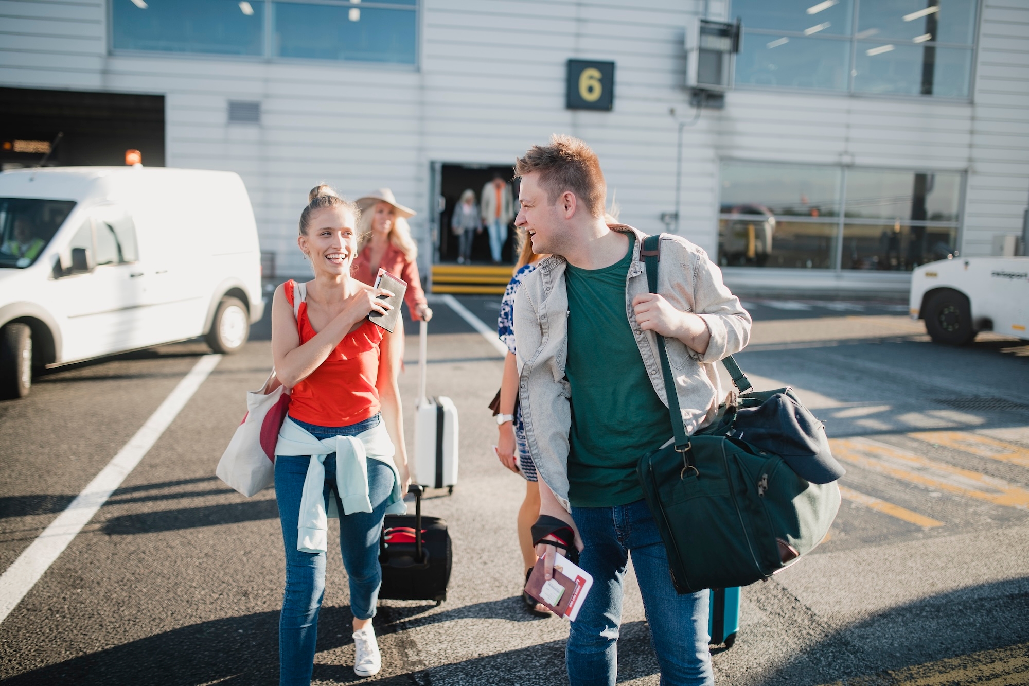  Young travelers with luggage stroll through the airport, ready to find their next flight adventure.