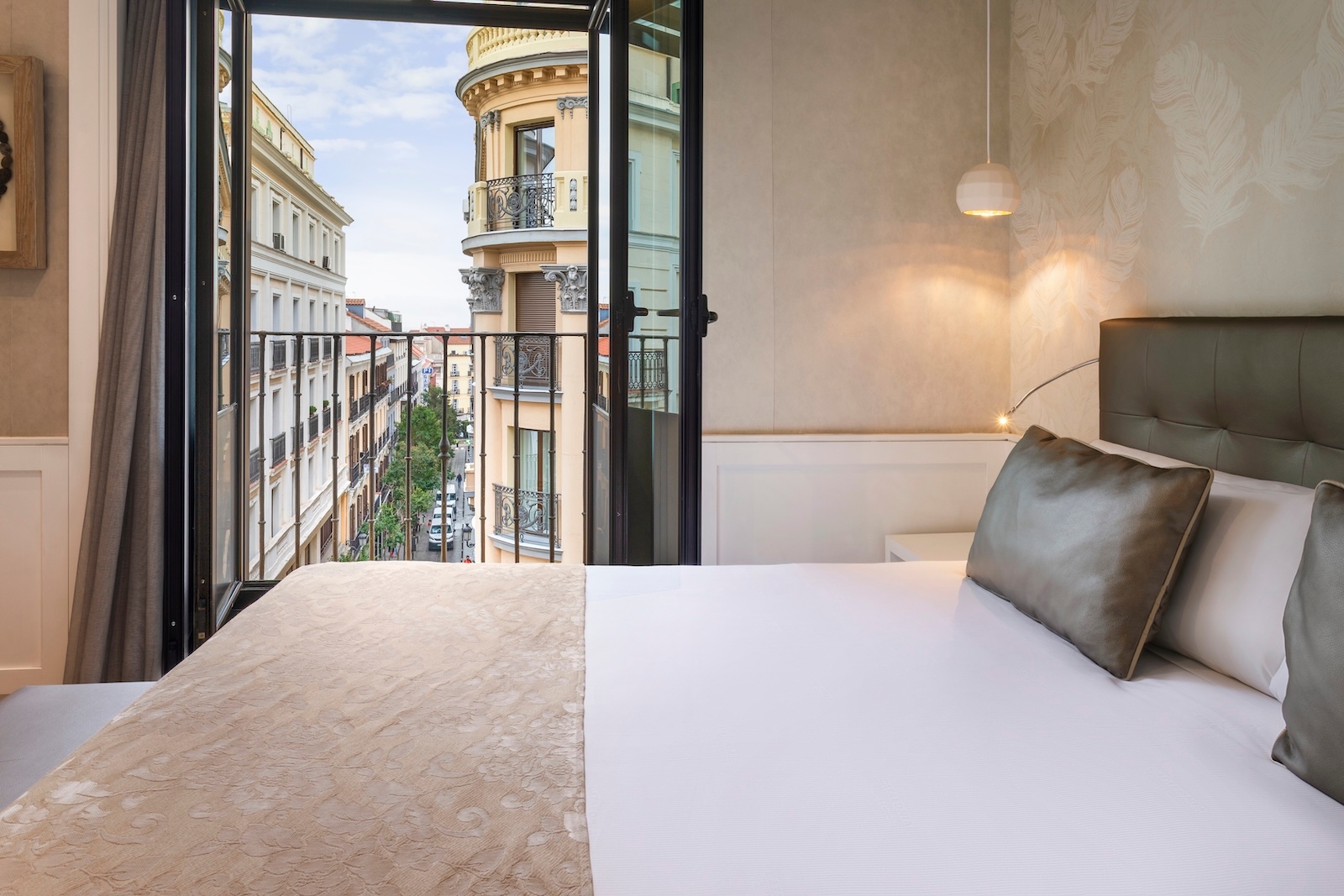 A cosy bedroom with a balcony offering a view of Madrid's city skyline, located in Catalonia Puerta del Sol