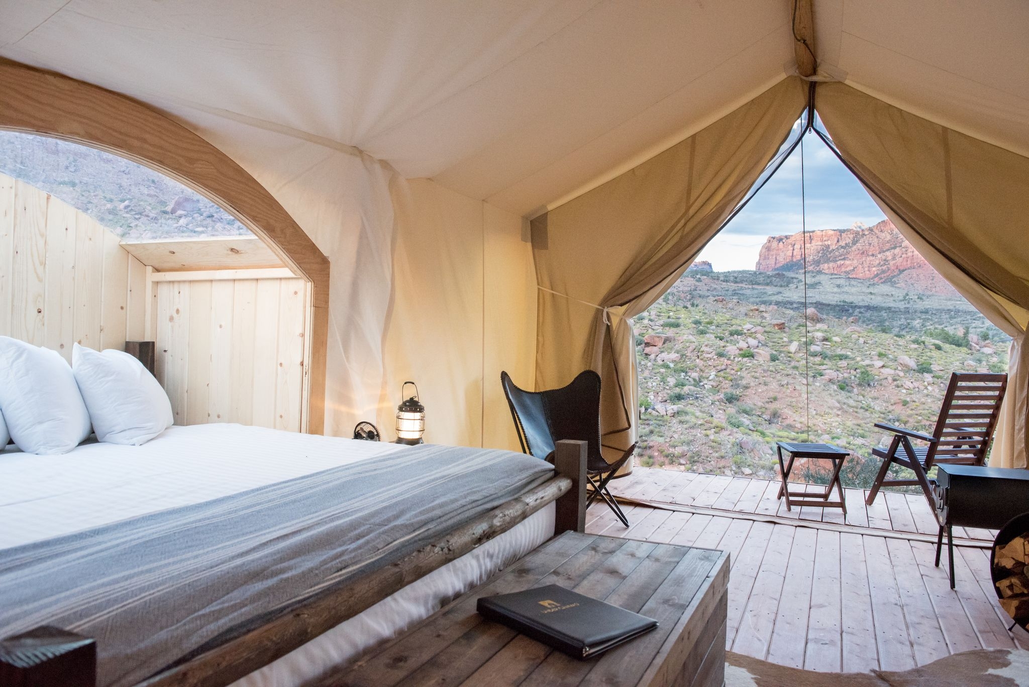 Cozy tent with a bed and a window showcasing stunning mountain views at Under Canvas Zion.