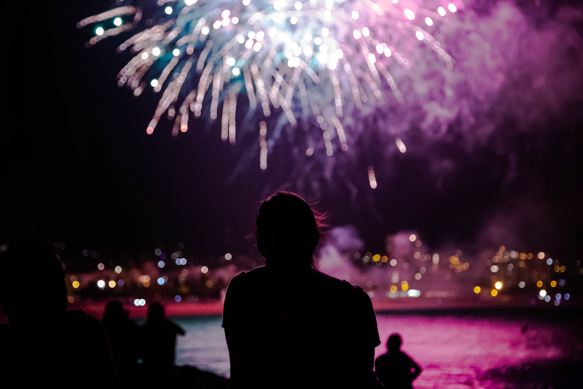 A person gazes at fireworks display in the night sky.