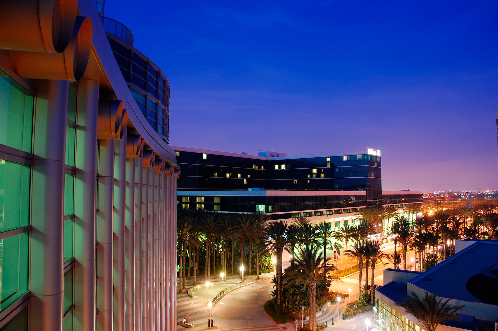 A nighttime view of a street near Disneyland California, featuring an illuminated cityscape in the background.