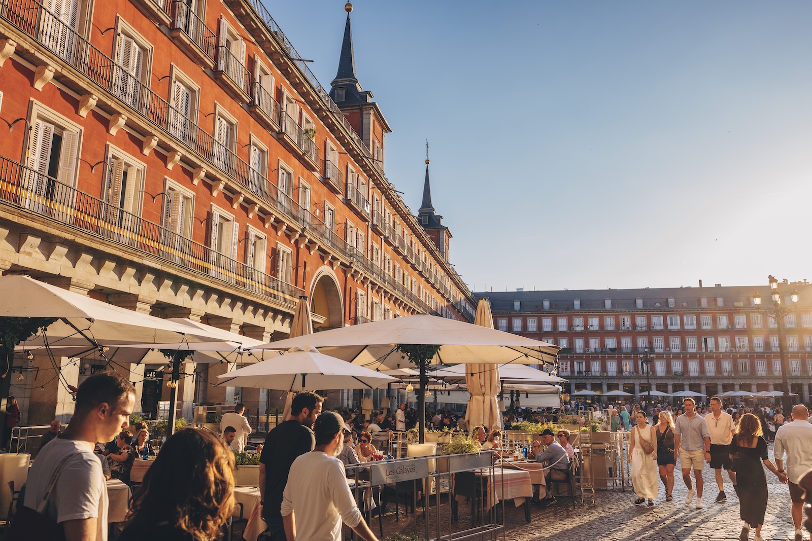 People stroll through Plaza Mayor in central Madrid, surrounded by historic architecture and vibrant atmosphere