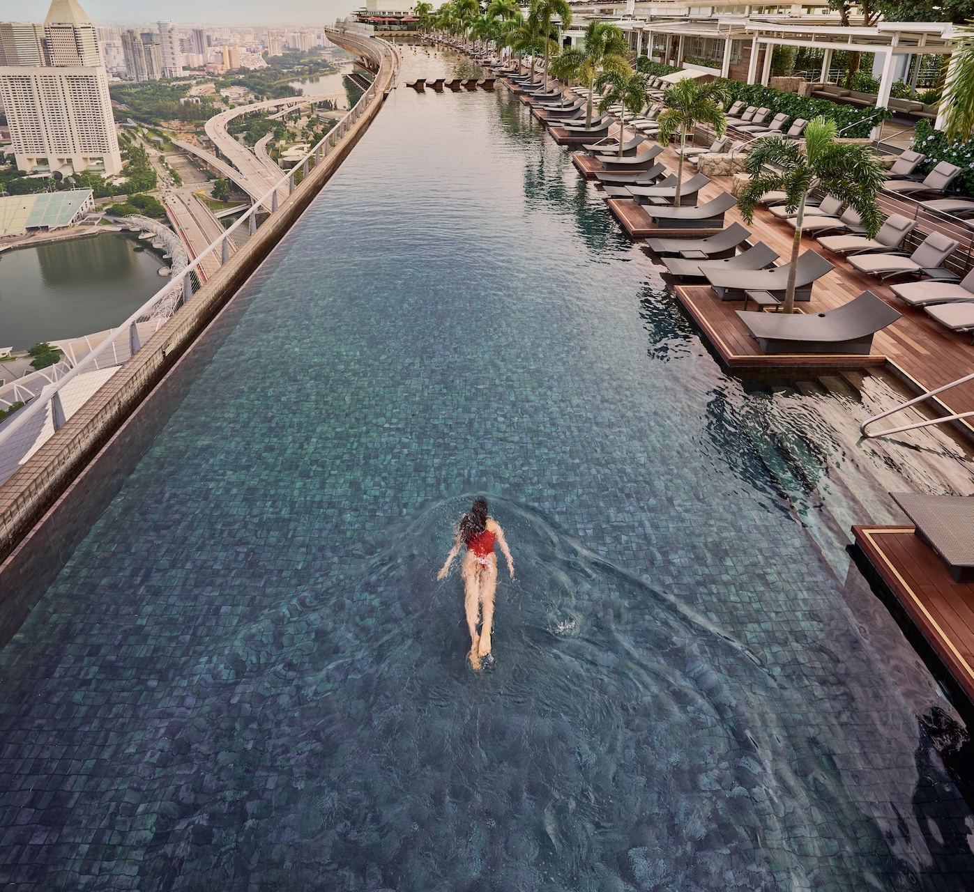 Eine Frau schwimmt im Pool der Unterkunft Marina Bay Sands, Singapur, und genießt den Blick auf die atemberaubende Skyline