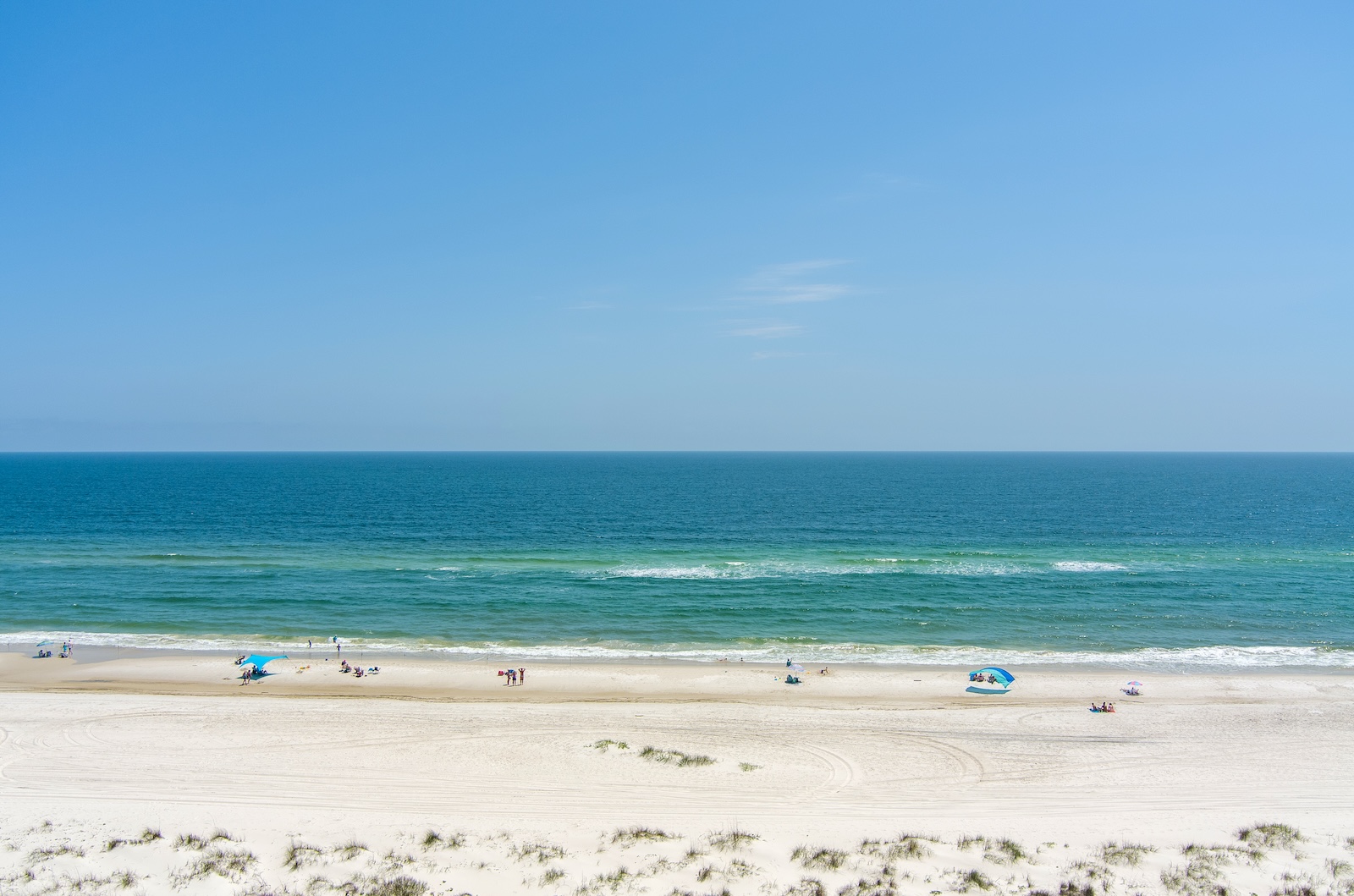 A picturesque view of Gulf Shores beach, showcasing white sand and a vibrant blue sky