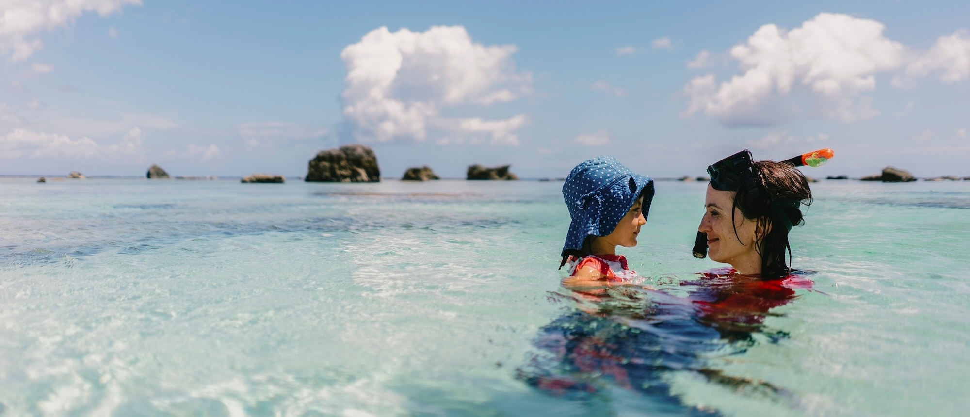 A mother and child share a moment of closeness in the sea