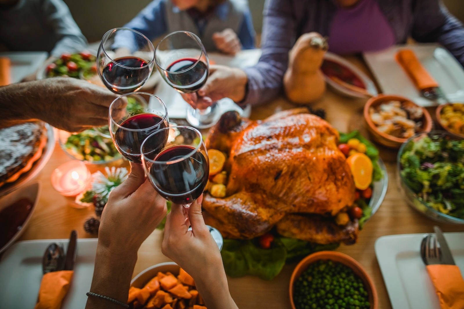 A festive Thanksgiving dinner table featuring turkey and wine, surrounded with friends, emphasizing the importance of checking dietary needs early