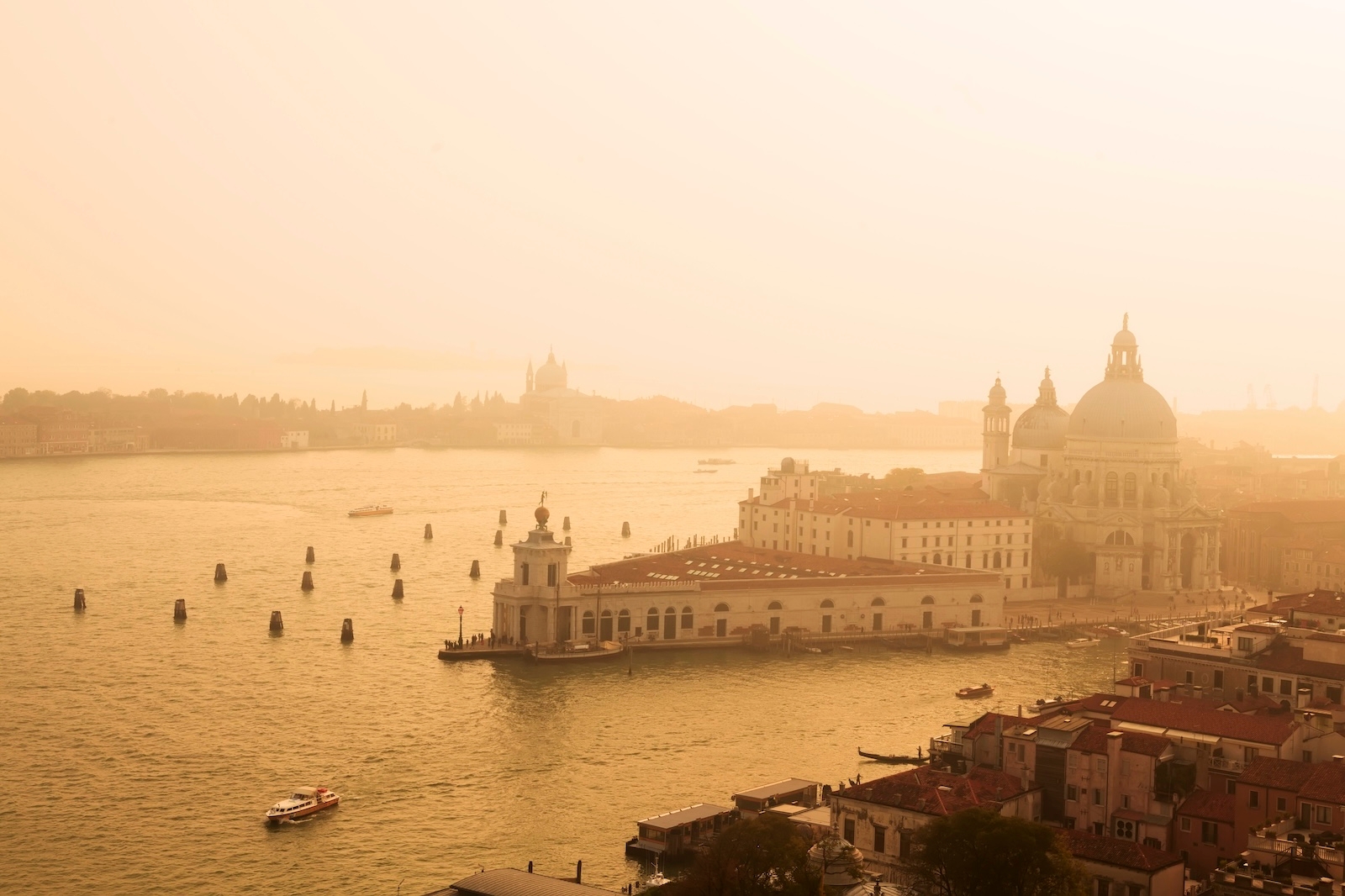 A panoramic view of Venice, showcasing Basilica Santa Maria in Dorsoduro against the cityscape – a very warm hue casts against the background
