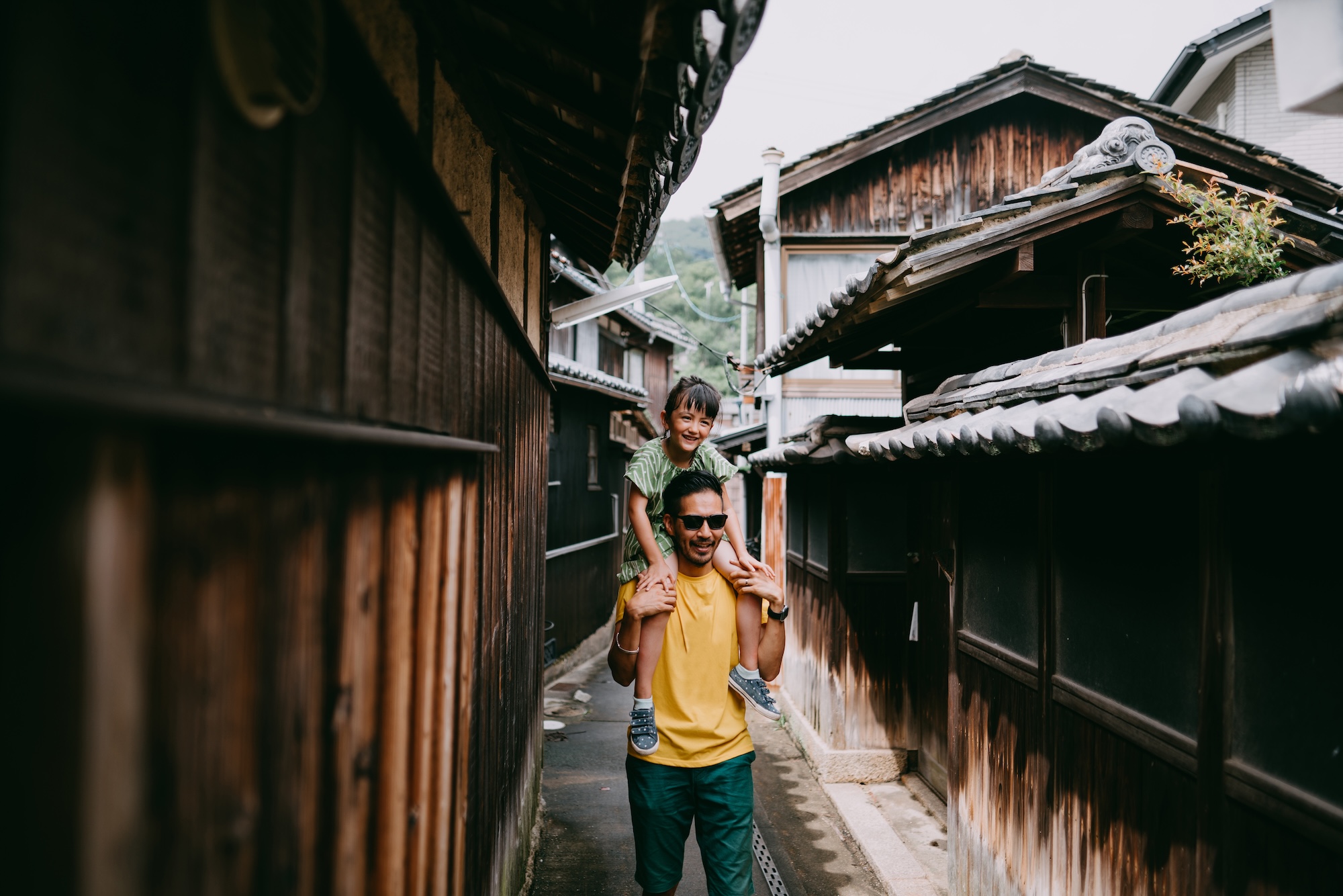 A father and daughter walk in a narrow alley in Japan