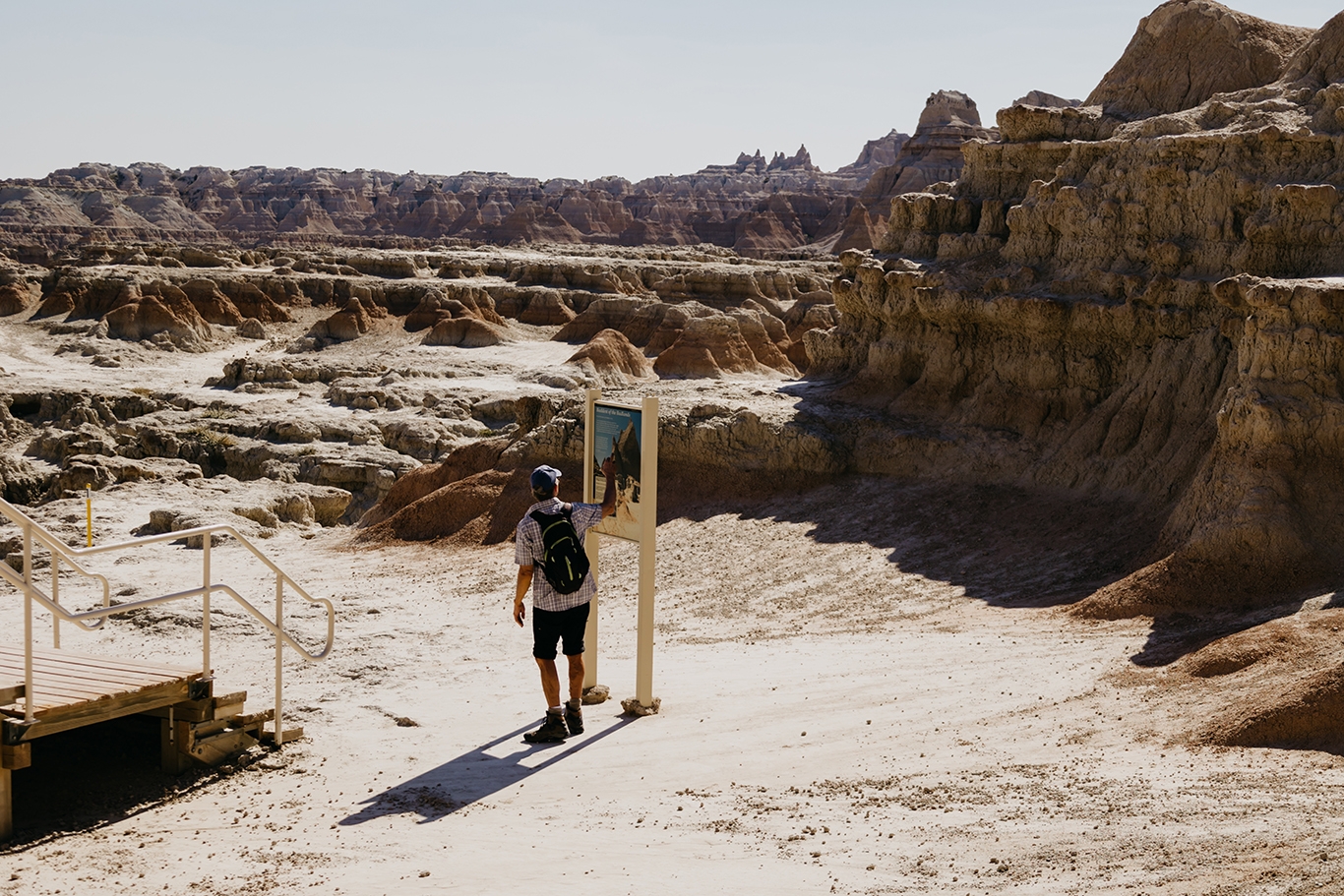A man stands gazes at a sign in the Badlands of South Dakota
