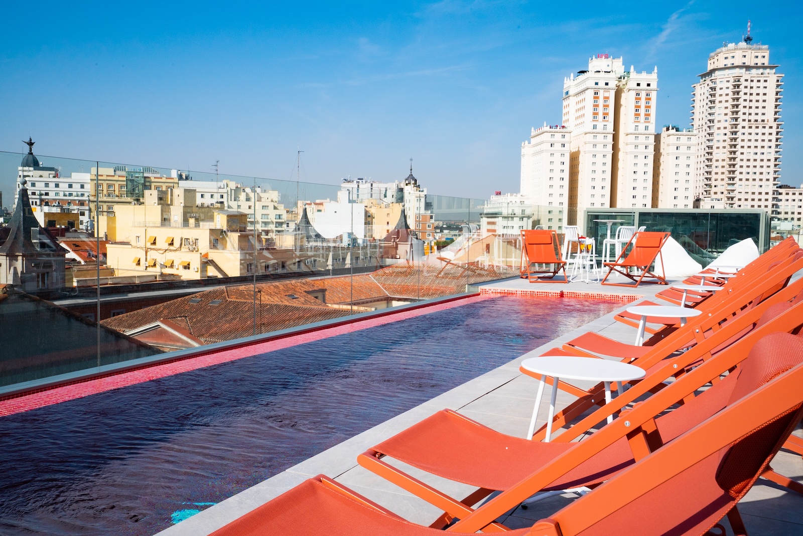 A poolside view at Akeah Hotel Gran Vía, featuring chairs and a panoramic view of the city skyline