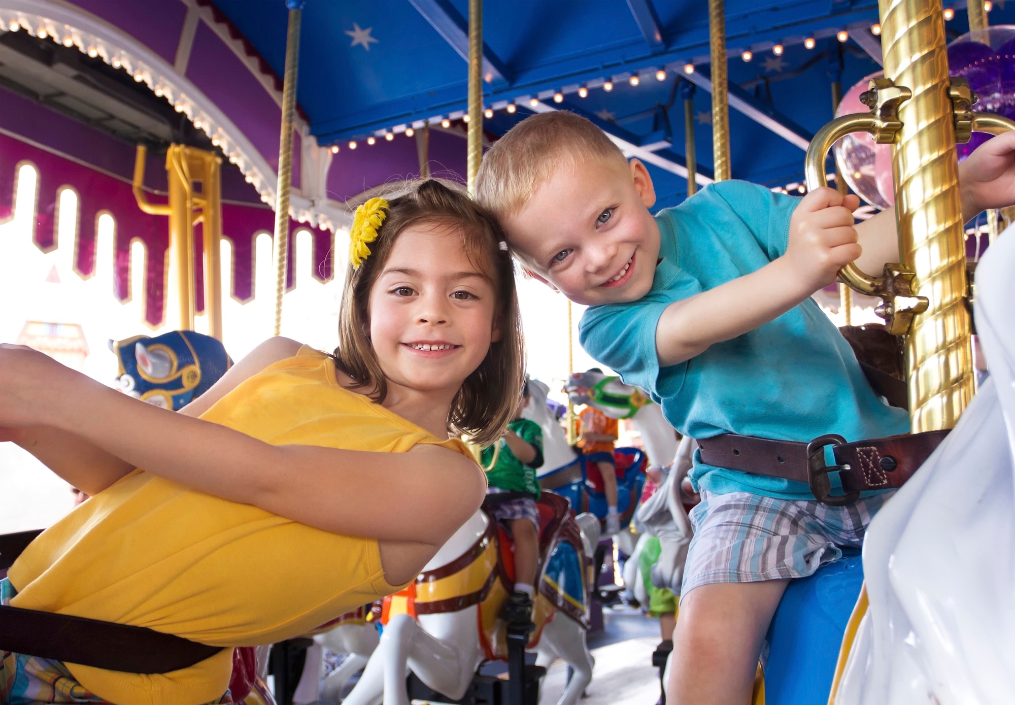 Two toddlers riding a colourful carousel at Disneyland