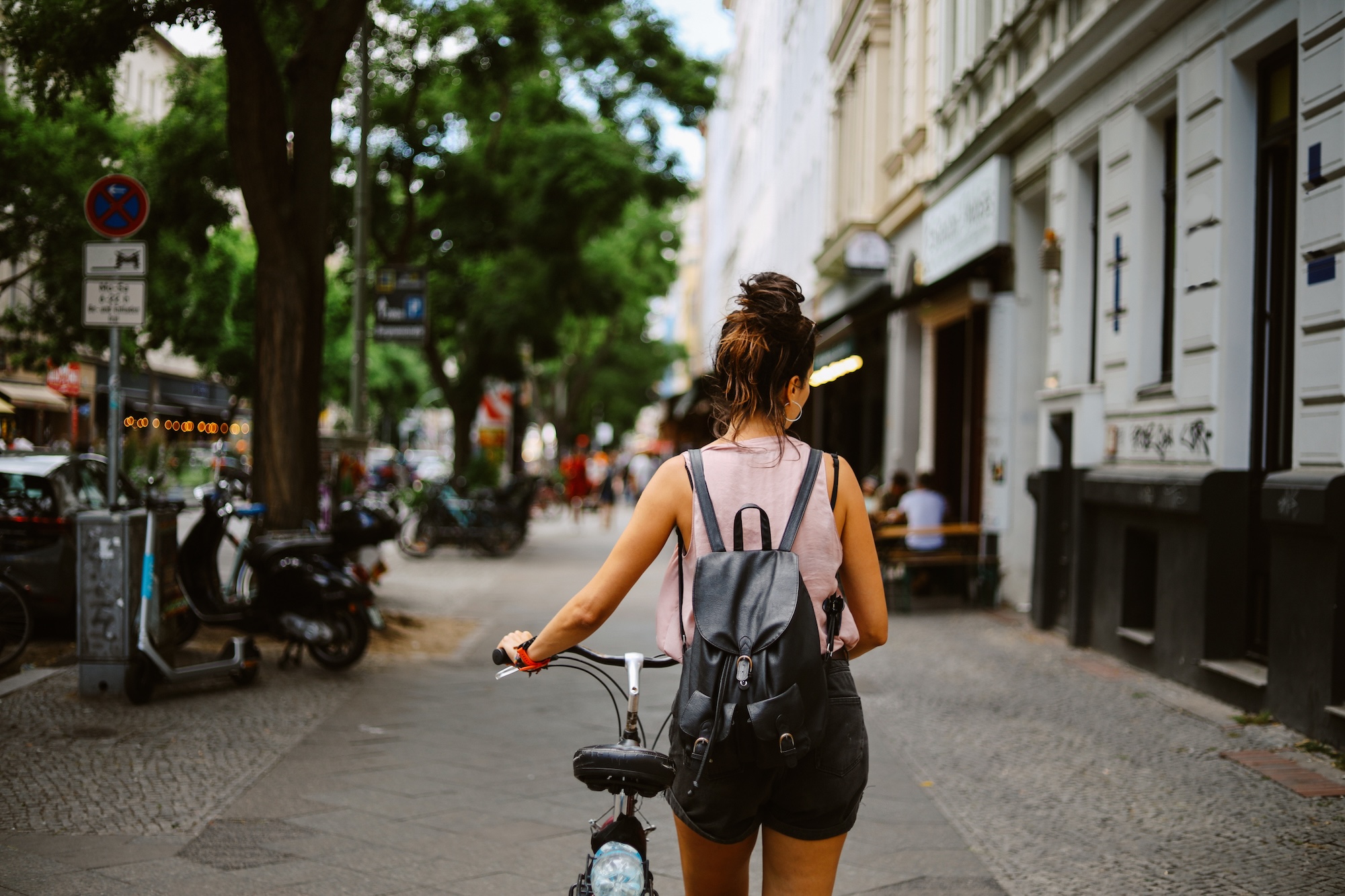 ドイツの路上で、バックパックを背負った女性が自転車を持っています。