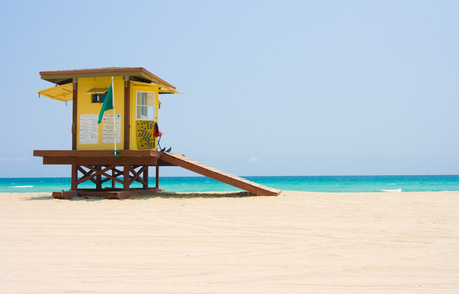 Lifeguard tower on Holly Beach under a clear blue sky, overlooking the sandy shore and ocean waves
