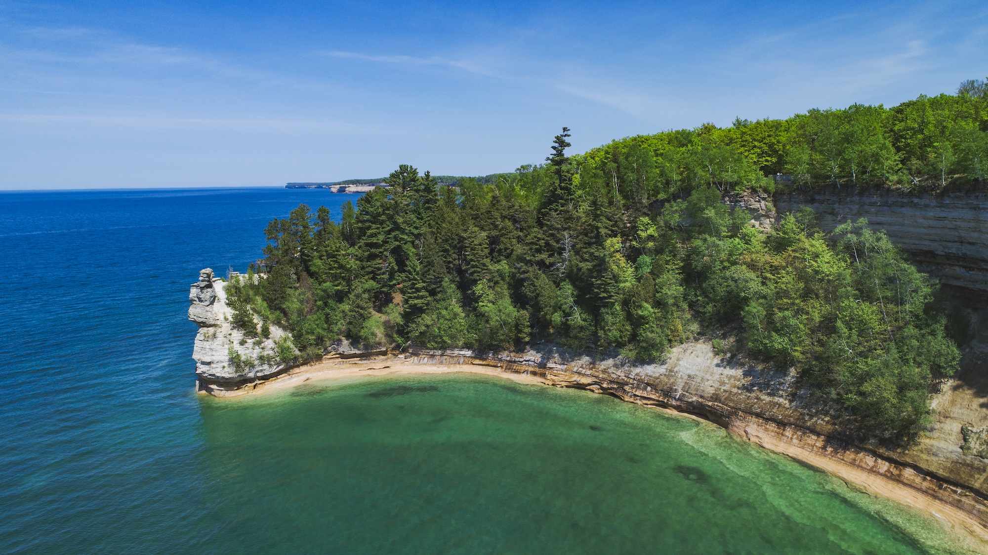 Scenic view of Twelvemile Beach, Michigan, featuring cliffs surrounded by lush trees and a serene lake.