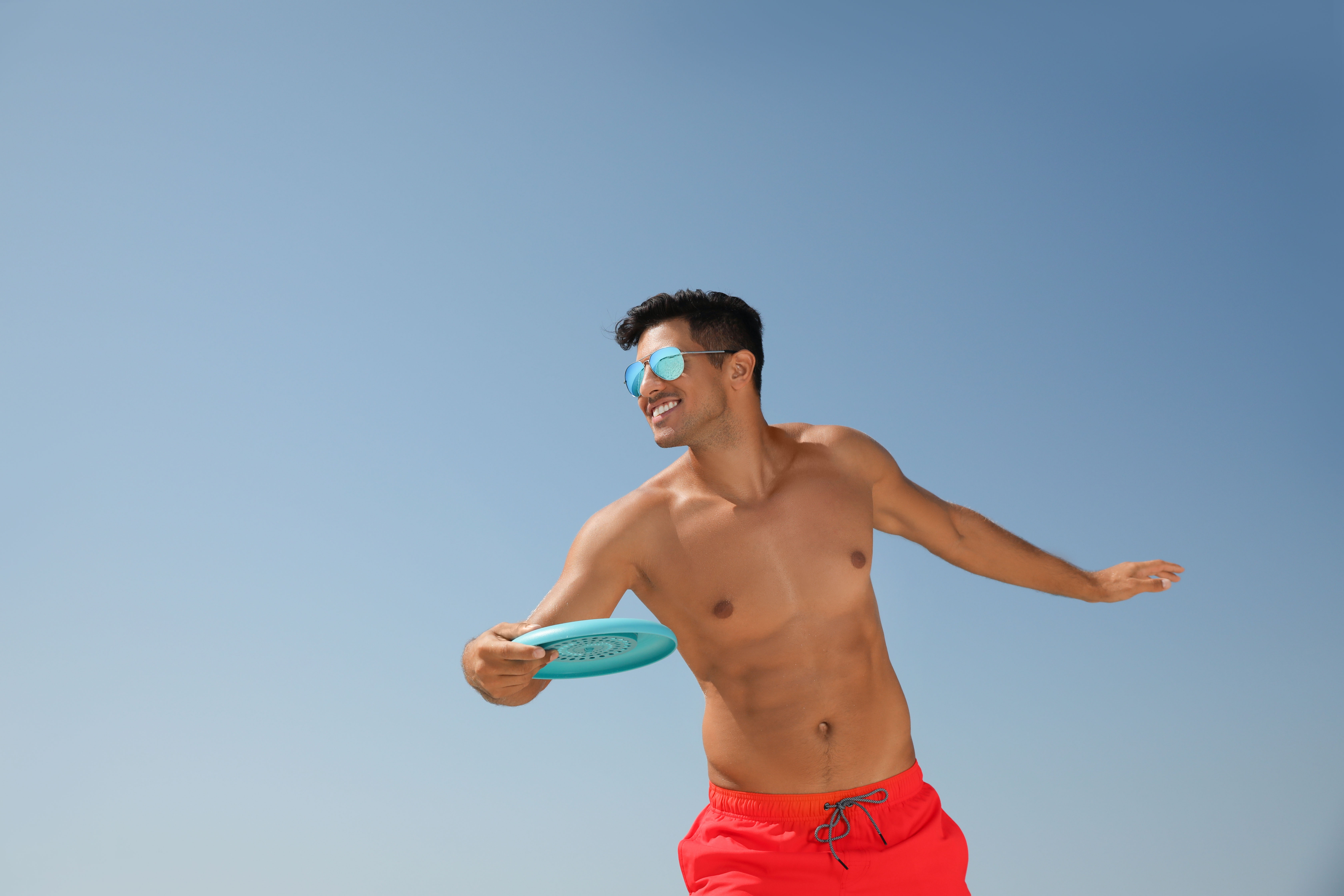 ragazzo in costume sorride e sta per lanciare un frisbee in un ambiente all’aperto