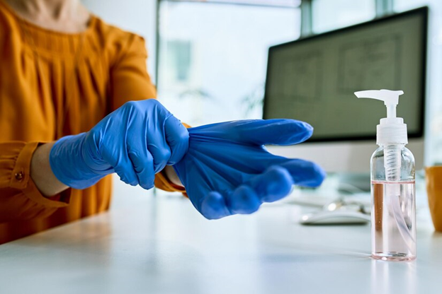 A person wearing gloves to clean with the help of antiseptic liquids