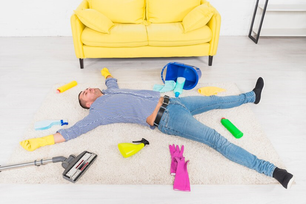 A man laying on the floor tired of cleaning with supplements all around him
