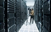 A woman works on a mobile laptop station in a server farm.