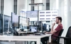 A man works at a desk full of computer monitors.