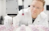 A worker in a white lab coat operates an industrial machine.