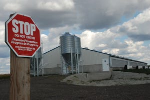 Foreboding clouds over hog barn with stop sign on post