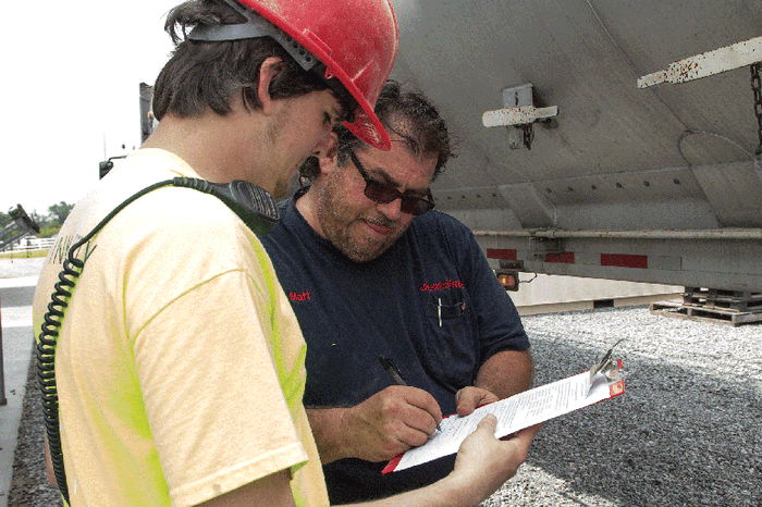 A feed mill employee gets the signature of an ingredient truck driver, which demonstrates safety of the product.