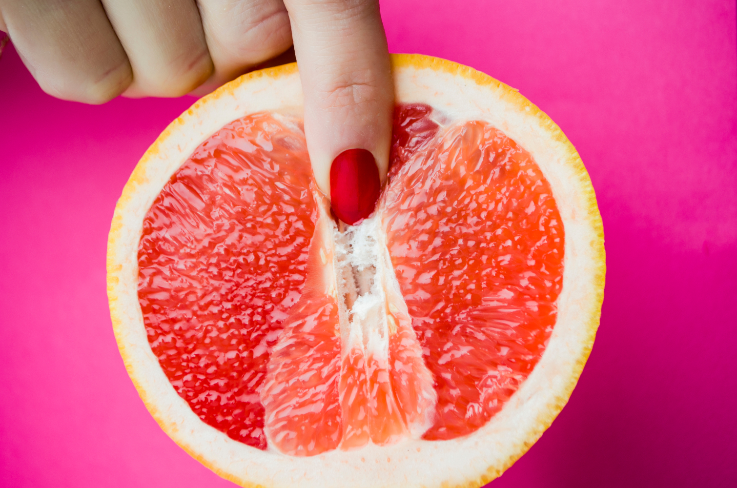 Dos dedos tocando una toronja simulando una vulva
