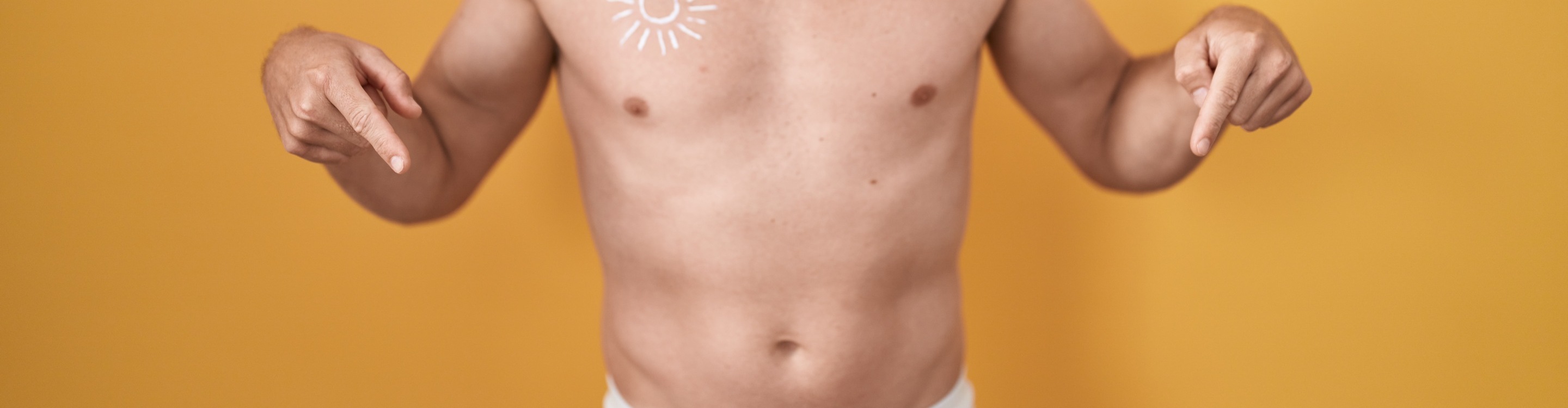 Bare torso with both hands pointing toward the lower abdomen against a yellow background