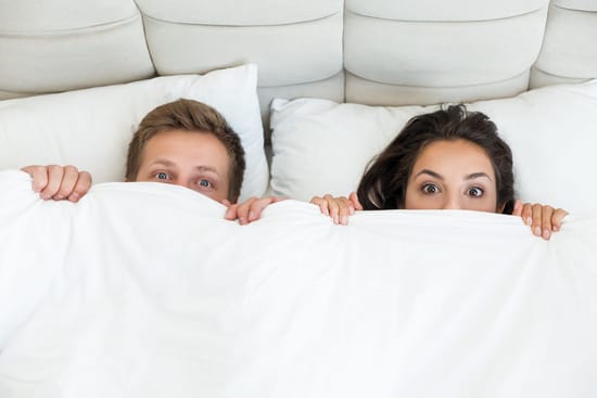 dos jovenes acostados en la cama sorprendidos