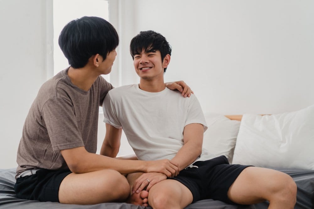 Couple on sitting on bed smiling at each other