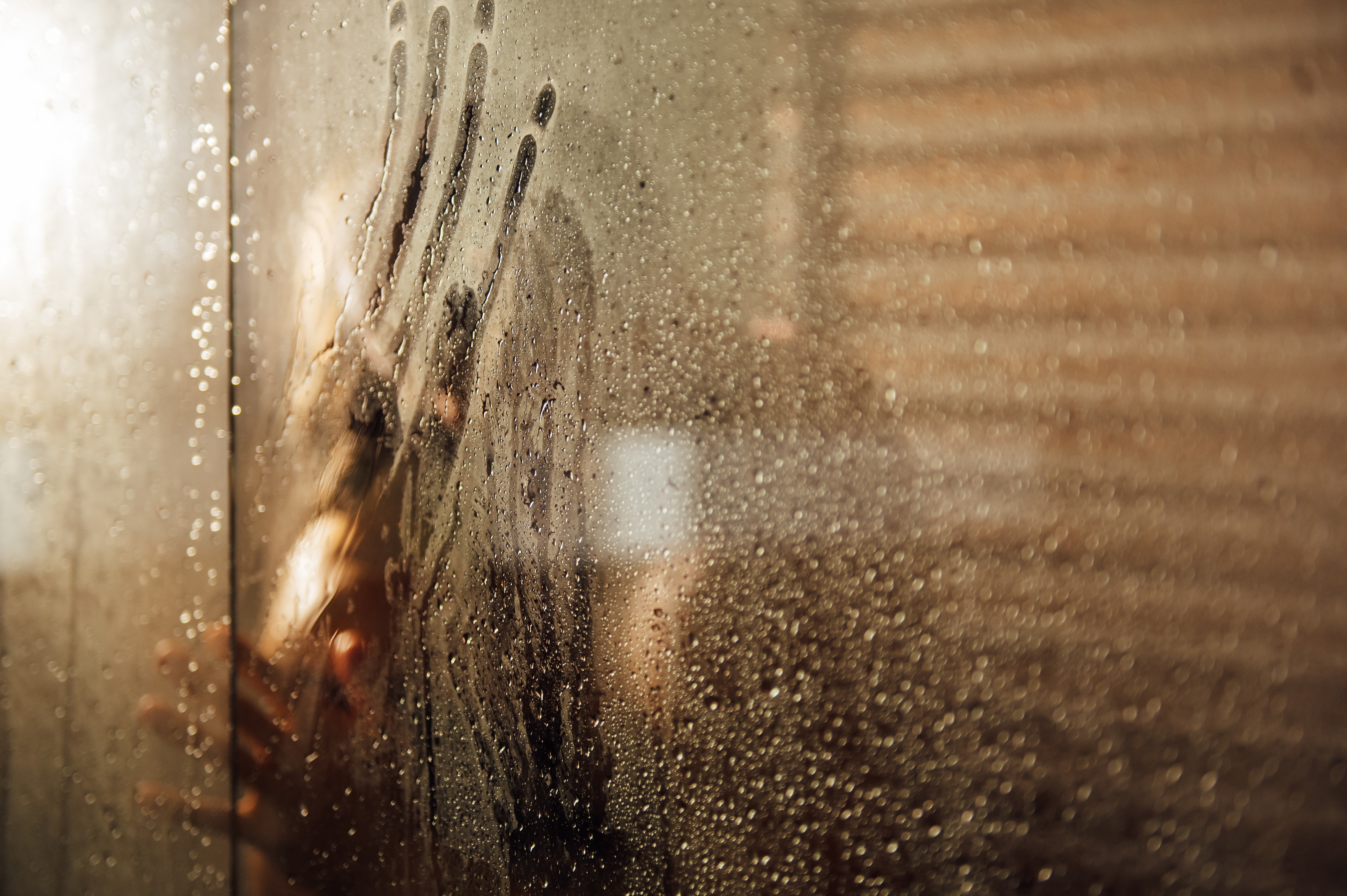 Silhouettes of two adults behind a steamed glass shower door