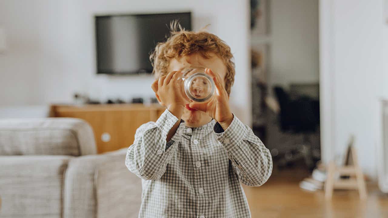 Kontrollierte Flüssigkeitszufuhr: Kind trinkt aus Glas Kontrollierte Flüssigkeitszufuhr: Kind trinkt aus Glas
