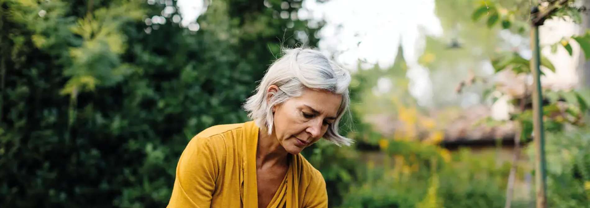 mein-krebsratgeber-chronisch-lymphatische-leukamie-hero Person mit grauem Haar in gelbem Oberteil in einer grünen Gartenumgebung