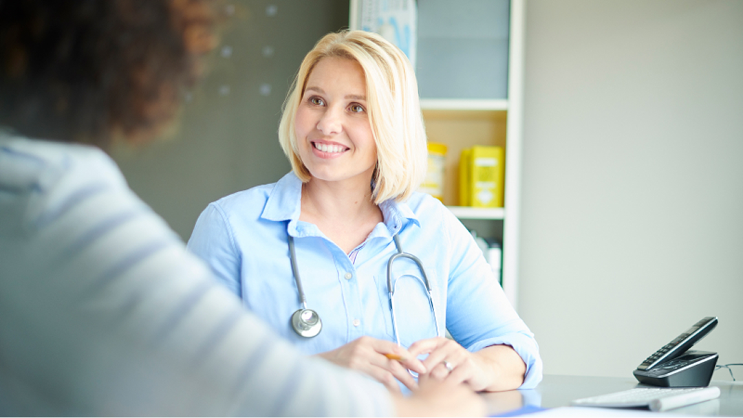 Eine Patientin spricht mit Ihrer Ärztin über die Symptome ihrer Psoriasis. 