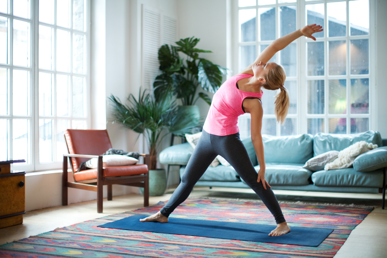 Eine Frau, die eine Yoga Übung in ihrem Wohnzimmer ausführt