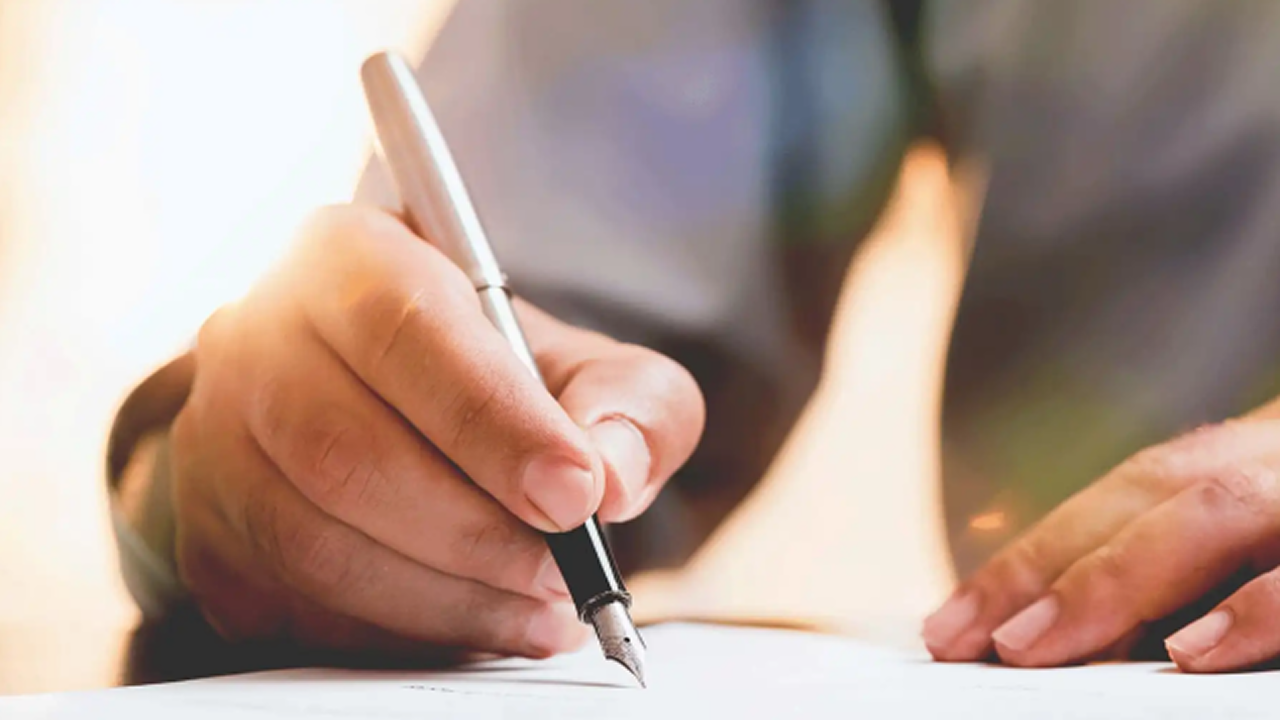 Person hält einen Füllhalter und unterschreibt damit ein Dokument