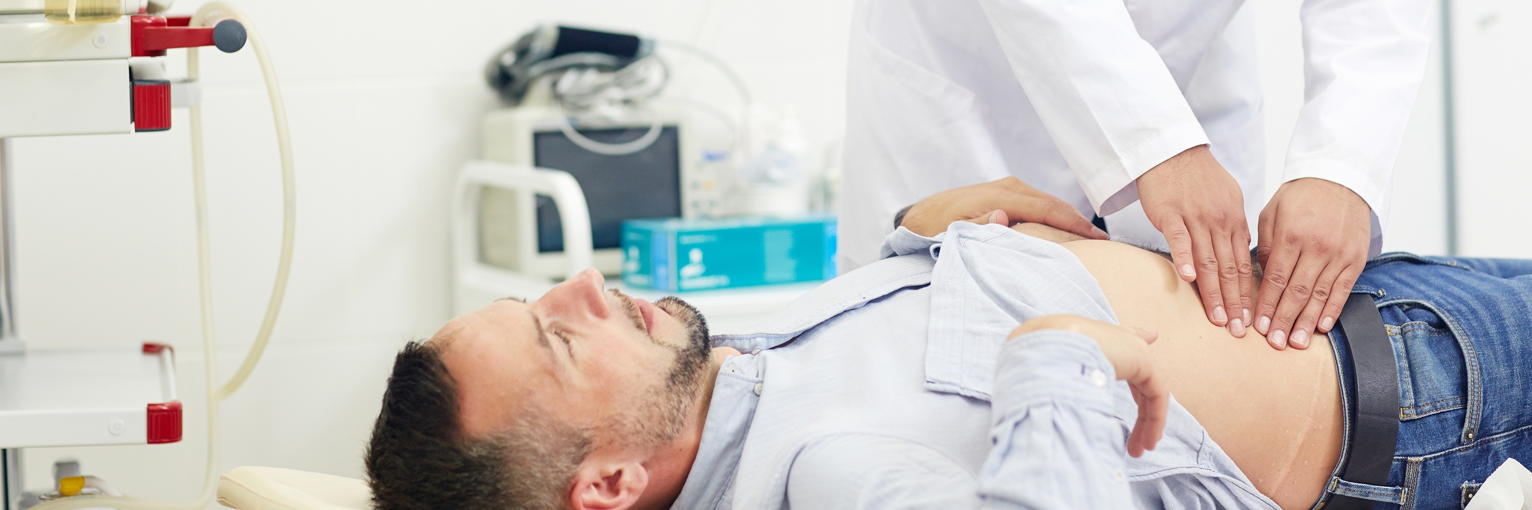 Arzt tastet bei einem Patienten den Bauchbereich ab.