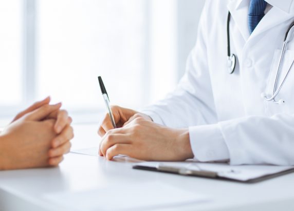 Arzt und Patientin mit Lungenkrebs sitzen sich in einem Behandlungsgespräch gegenüber.